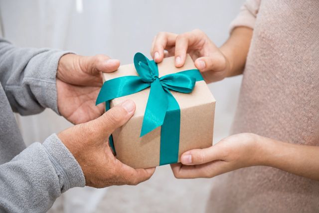 Gift being exchanged with a PS teal ribbon