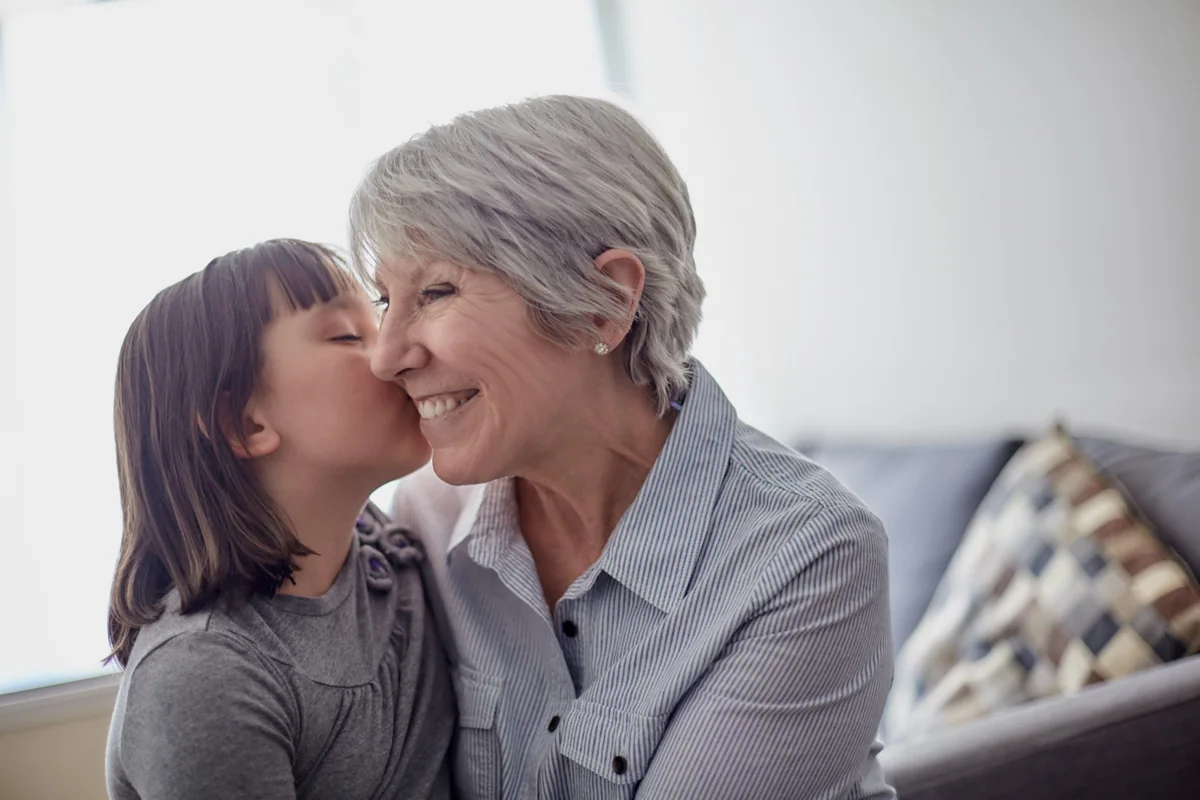 A young family member kissing an older family member on the cheek